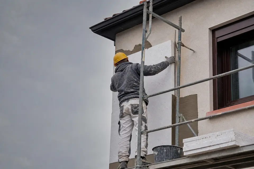 Exemple : ouvrier appliquant un enduit de façade depuis un échafaudage